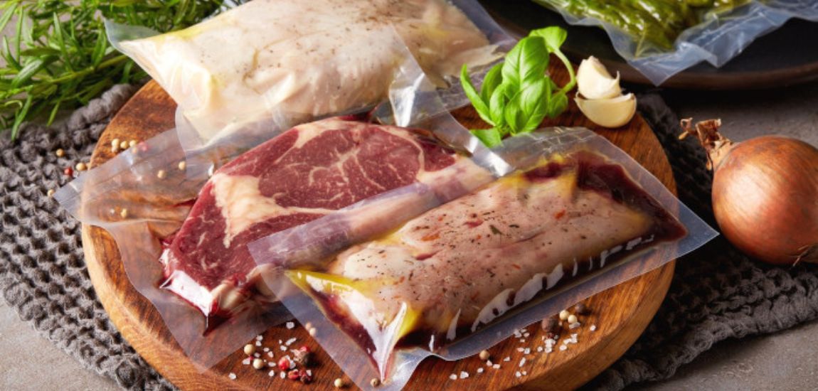 Worki próżniowe FoodSaver z zamarynowanym mięsem, leżące na drewnianej desce do krojenia