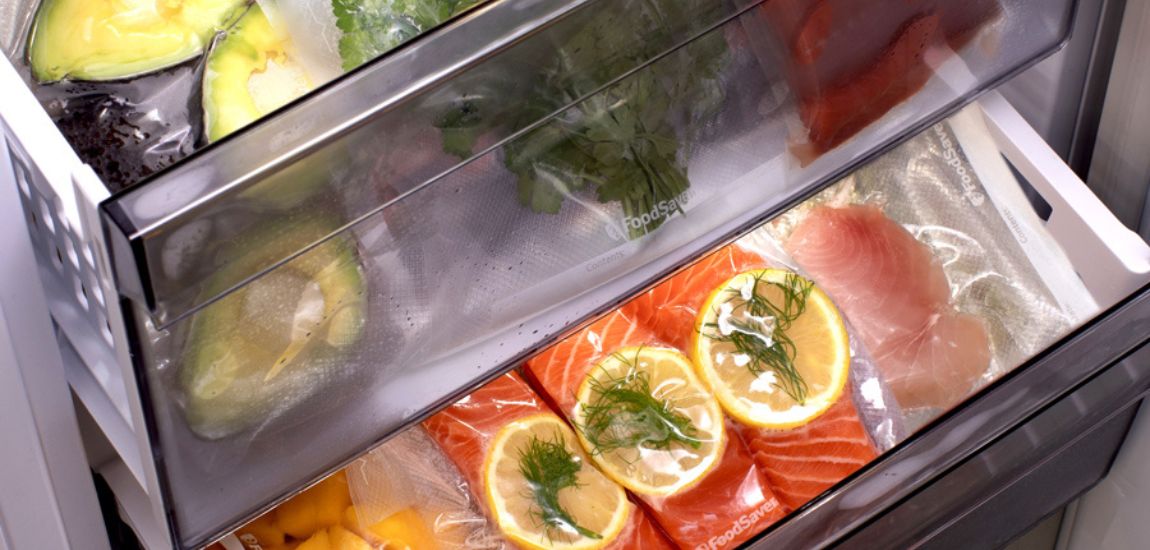 Trzy kawałki łososia z cytryną oraz awokado zapakowane próżniowo w workach FoodSaver starannie ułożone w zamrażarce